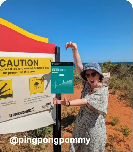 Woman holding her phone next to a caution sign at the beach