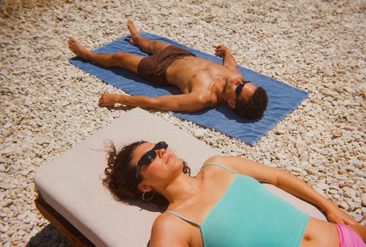 Two people relaxing in the sun on a pebble beach